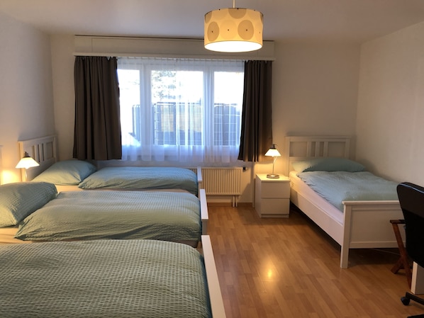 Habitación de hotel con dos camas, un escritorio, una silla y una ventana con cortinas.