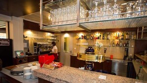 Zona de bar con mostrador, platos apilados y un bartender preparando bebidas.
