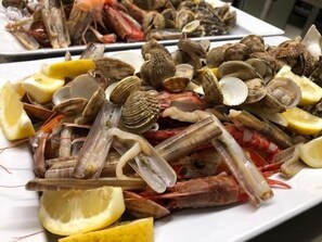Una bandeja de mariscos con almejas, camarones y rodajas de limón.