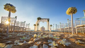 A beach wedding setup with a white arch, chairs, and floral decorations. - Rena Resort (Mondragone)