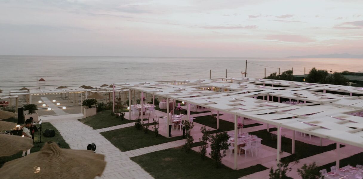 An outdoor terrace with tables and chairs, overlooking the sea.