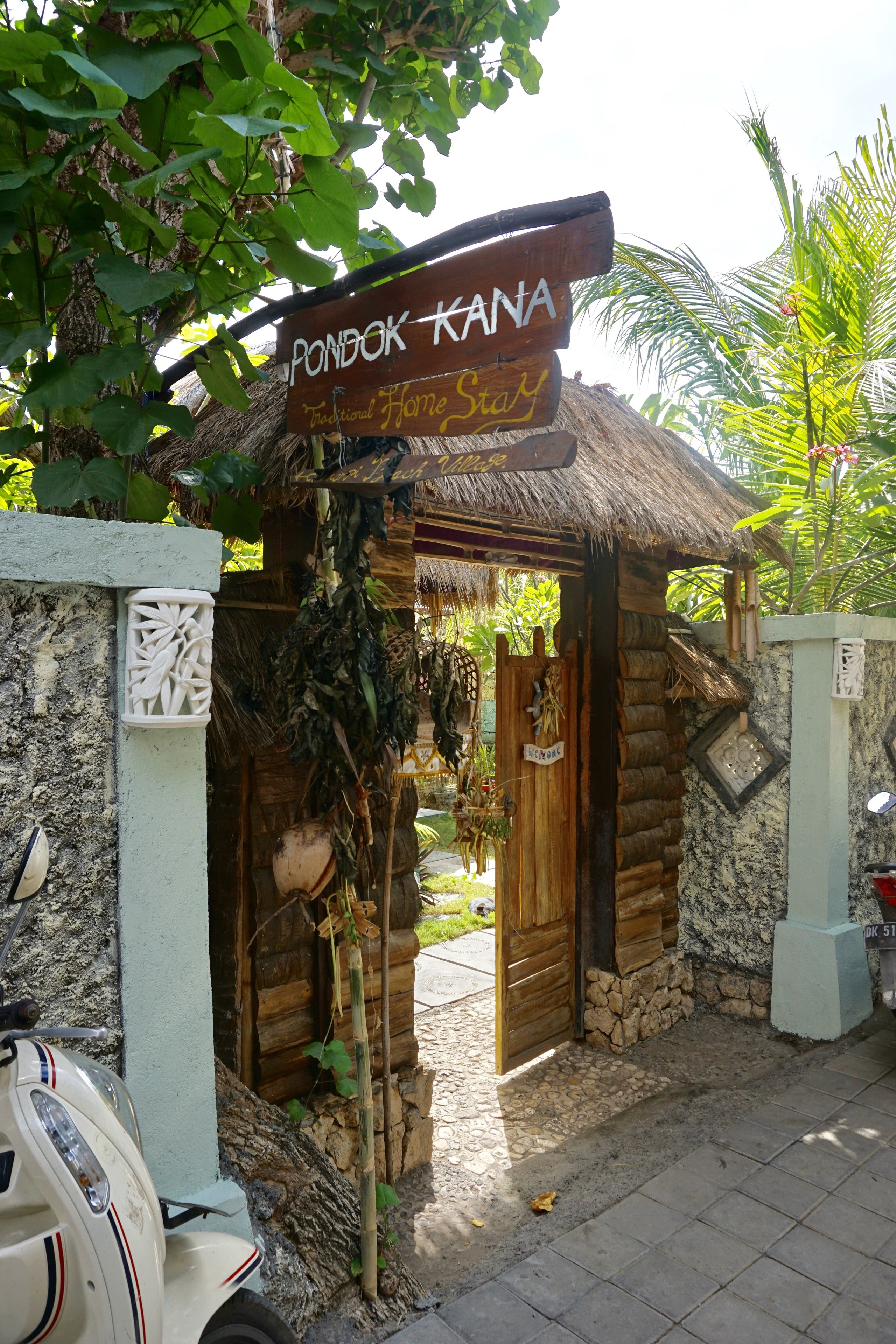 Une structure traditionnelle en bois, sur laquelle est apposée une enseigne indiquant : « Pondok KANA, hébergement traditionnel. »