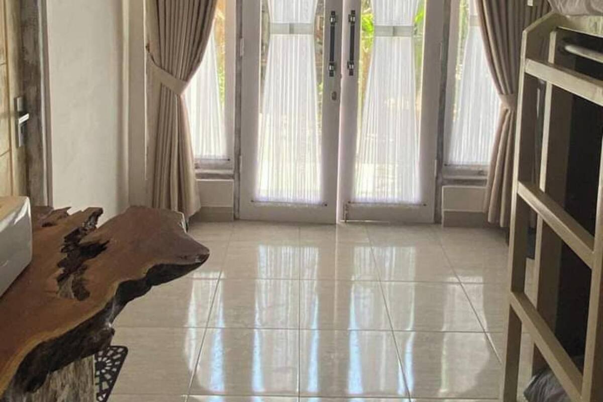A spacious room with a large wooden table, a cabinet with shelves, and a pair of double doors with curtains.