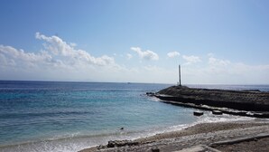 A coastal view with a rocky breakwater and a lighthouse. - Pondok Kana Homestay (Penida Island)