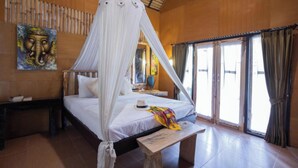 A bedroom with a canopy bed, a wooden headboard, a bedside table, a nightstand, a bench, and a large window with curtains. - Pondok Kana Homestay (Penida Island)