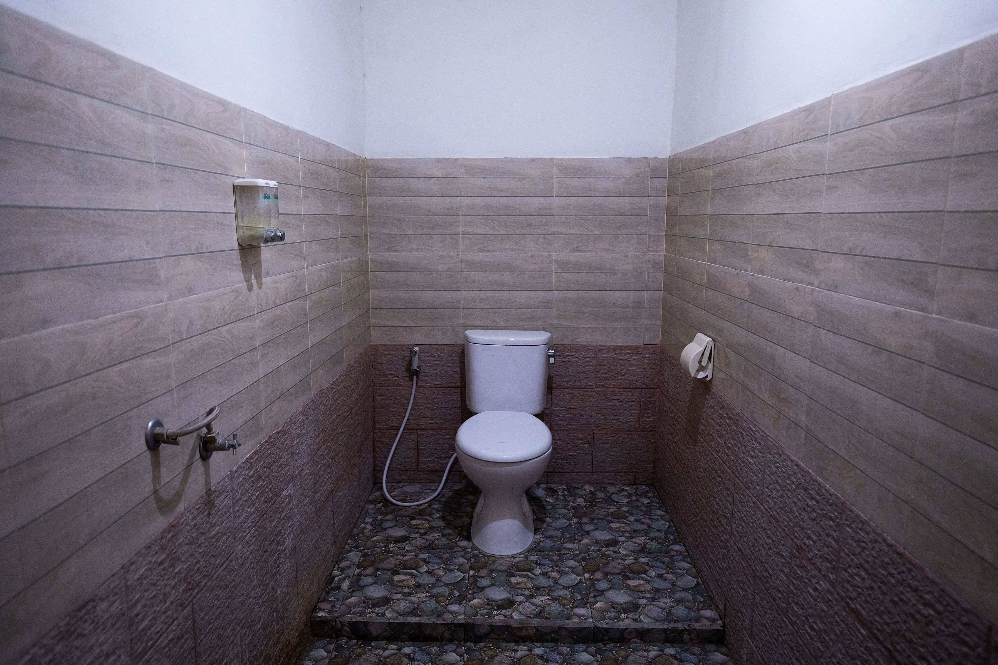 A small bathroom with a toilet, a hand dryer, and a paper towel dispenser.