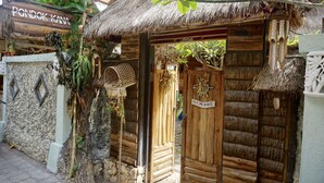 A traditional wooden structure with a thatched roof, a sign reading "PONDOK KANA," and a wooden door with a sign above it. - Pondok Kana Homestay (Penida Island)