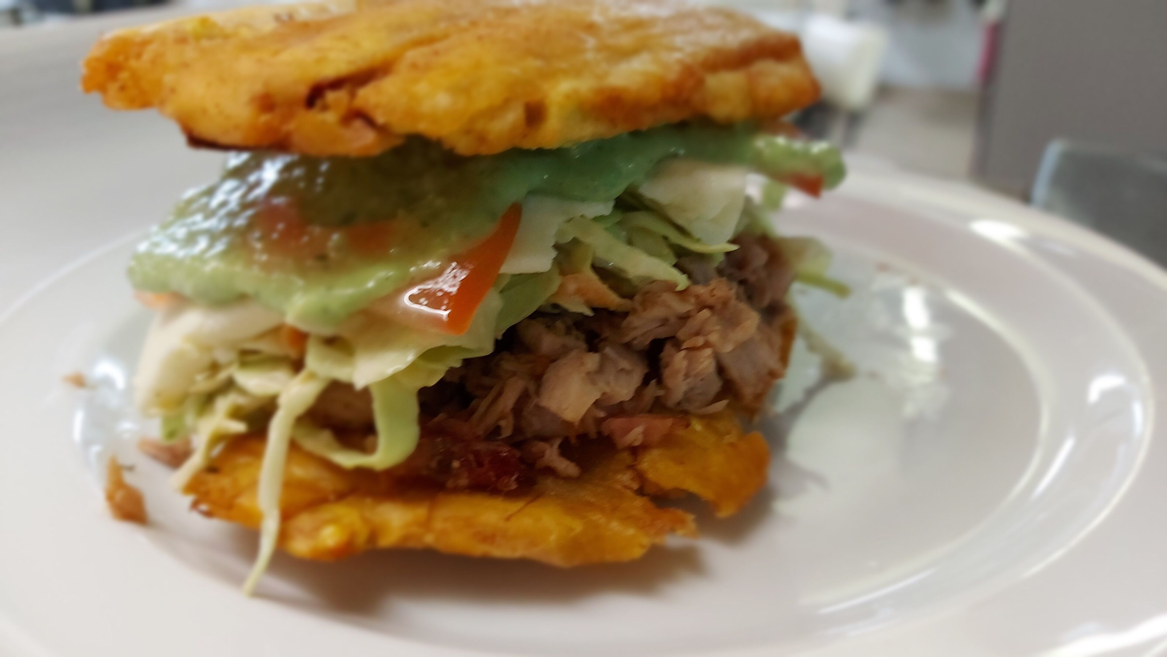 Ein Sandwich mit Salat, Tomate und Fleisch auf einem weißen Teller.