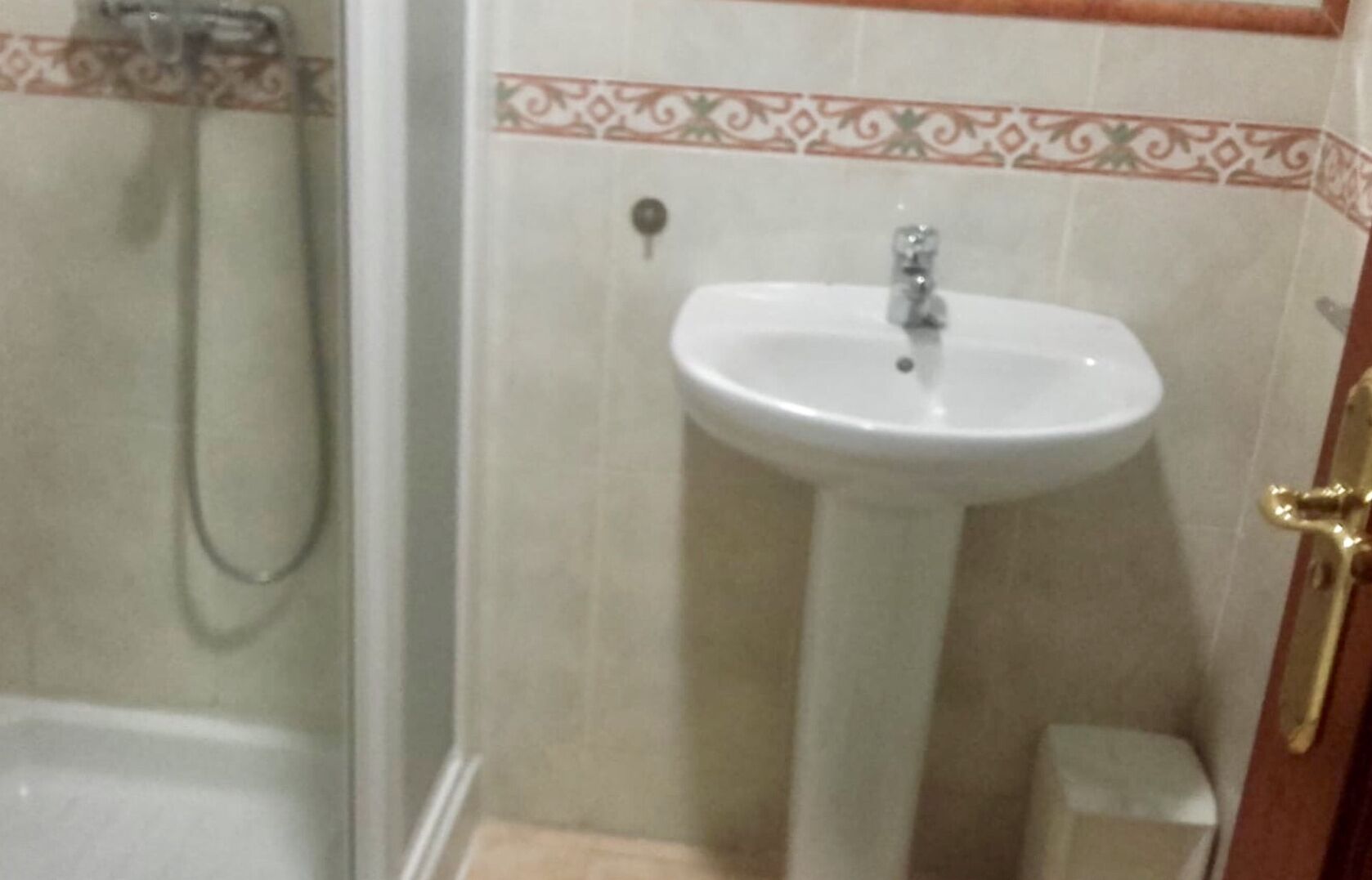 Un baño con ducha, lavamanos pedestal y retrete.