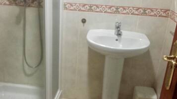 Un baño con ducha, lavamanos pedestal y retrete.