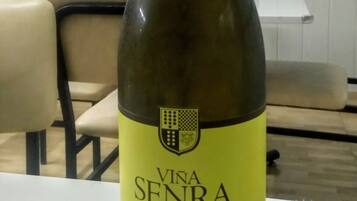 Una botella de vino Vina Senra sobre una mesa en una habitación con un cuadro en la pared y un radiador.