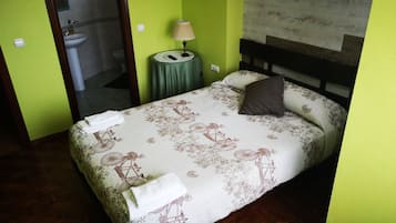 Una cama con colcha estampada, una lámpara de noche y una almohada.