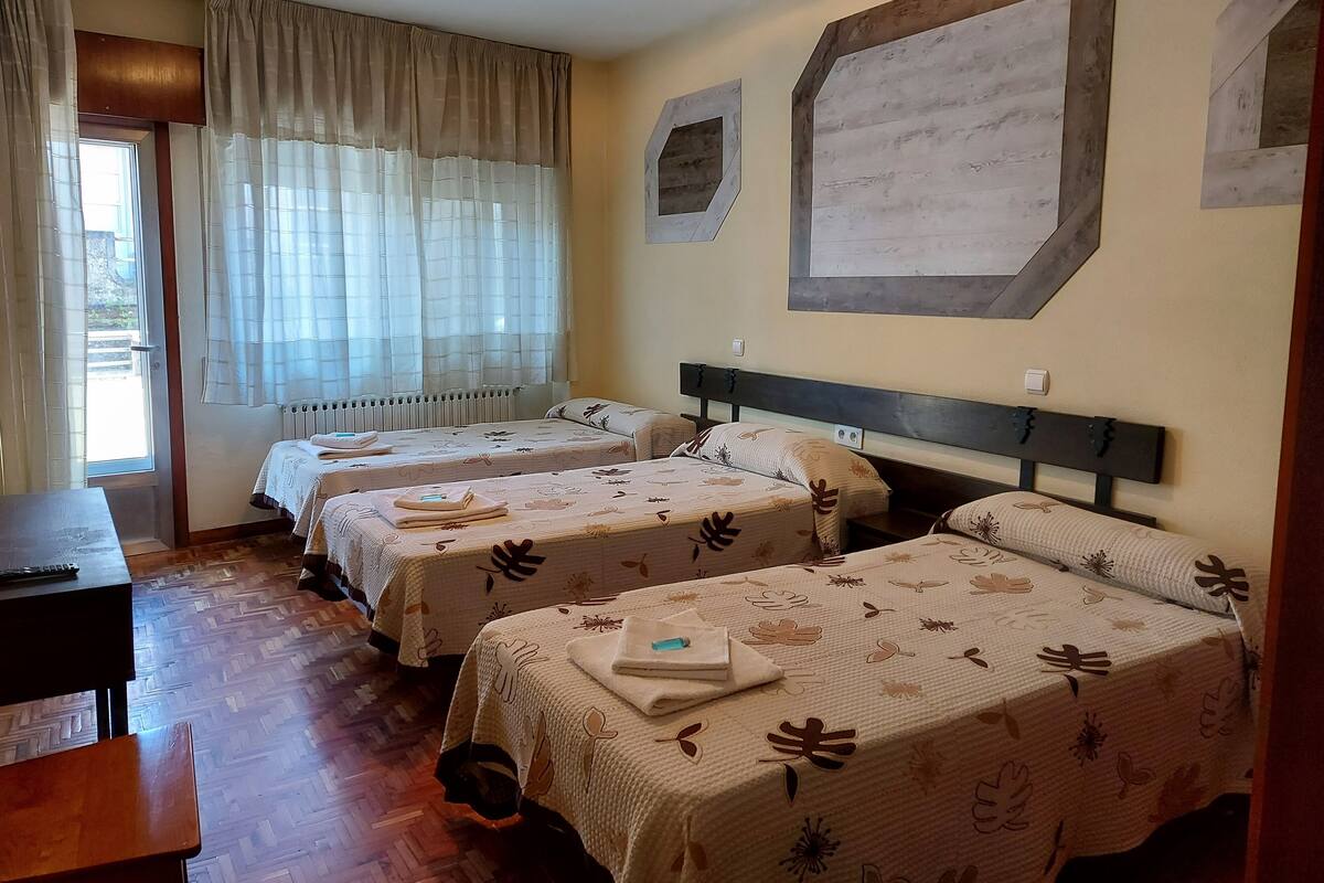 A hotel room with two beds, a desk, and a window with curtains.
