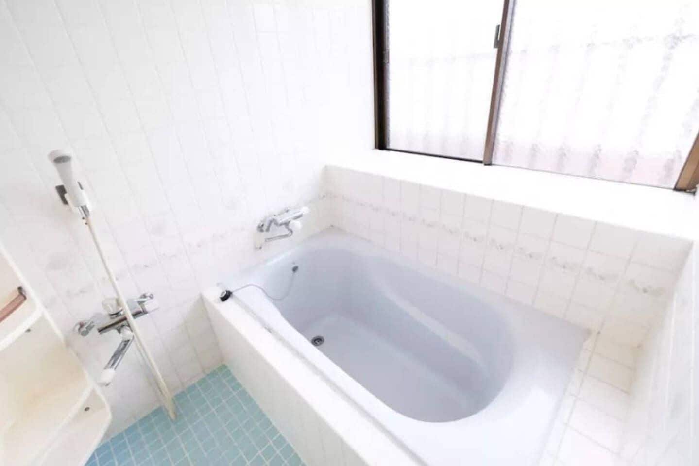 A bathroom with a bathtub, a shower, and a window.