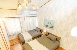 A room with two beds, a wooden floor, a ceiling light fixture, and a wall-mounted air conditioner. - Terrace House Tsubokawa (Naha)