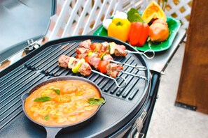 A grill with skewers of meat and a bowl of soup. - Terrace House Tsubokawa (Naha)