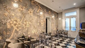 Uma sala de jantar moderna com piso xadrez, cadeiras transparentes e um design floral na parede.