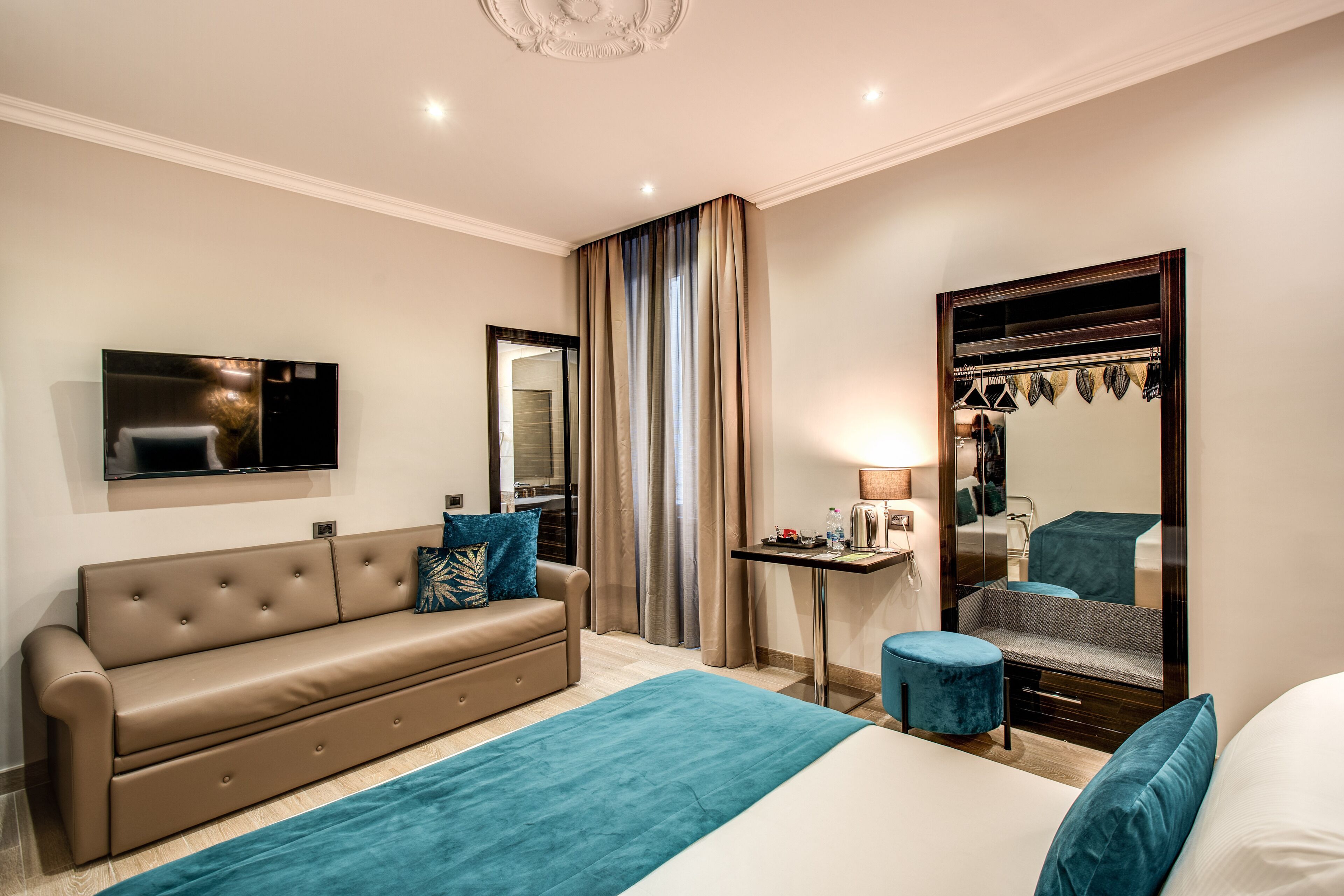 Una habitación de hotel moderna con sofá, cama, escritorio y espejo.