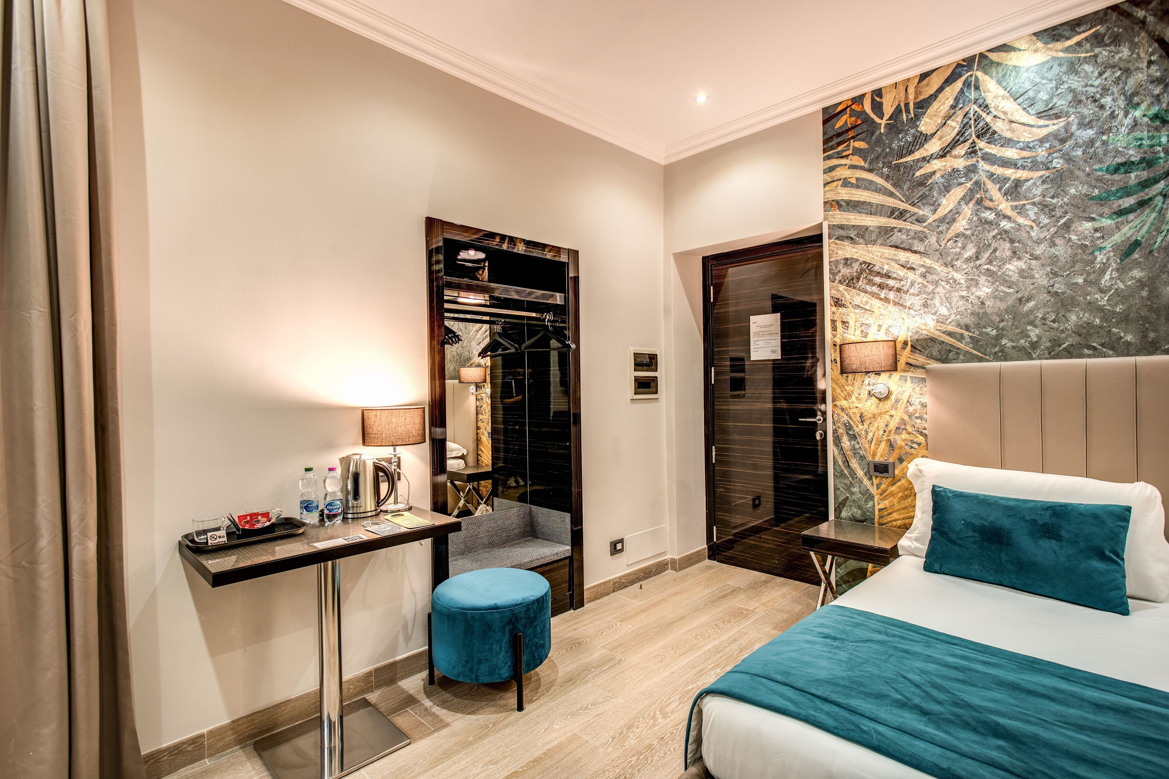 A modern hotel room with a bed, a desk, a chair, and a small ottoman.