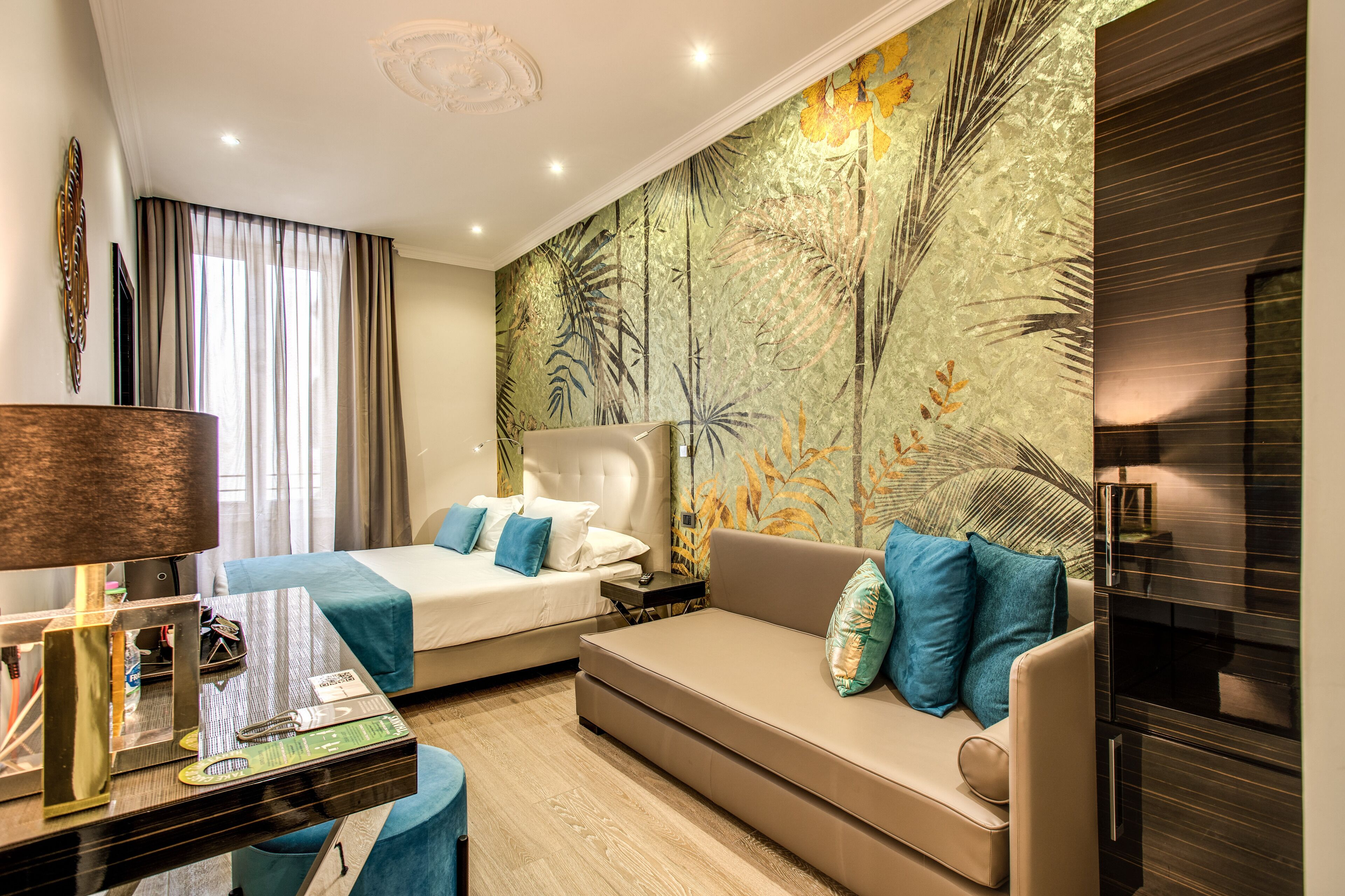 Une chambre d’hôtel avec un lit, un canapé, un bureau et une grande fresque murale.