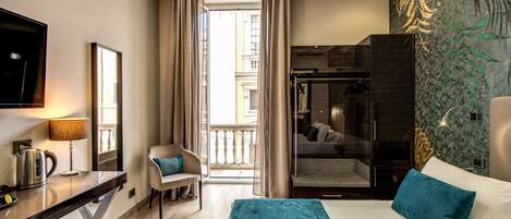 A modern hotel room with a bed, a desk, a chair, a TV, and a balcony view.