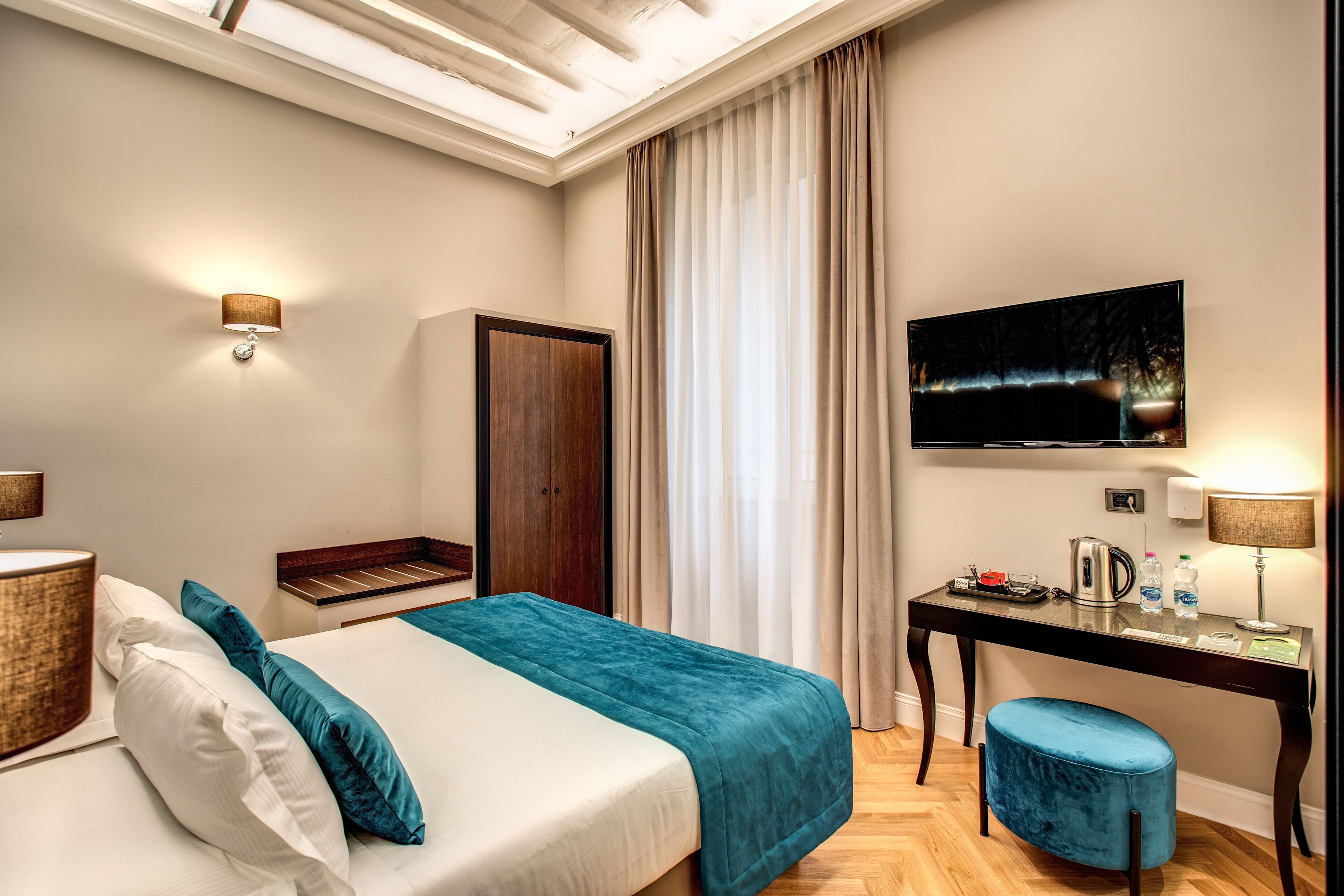 Una habitación de hotel con cama, escritorio, televisor y armario.