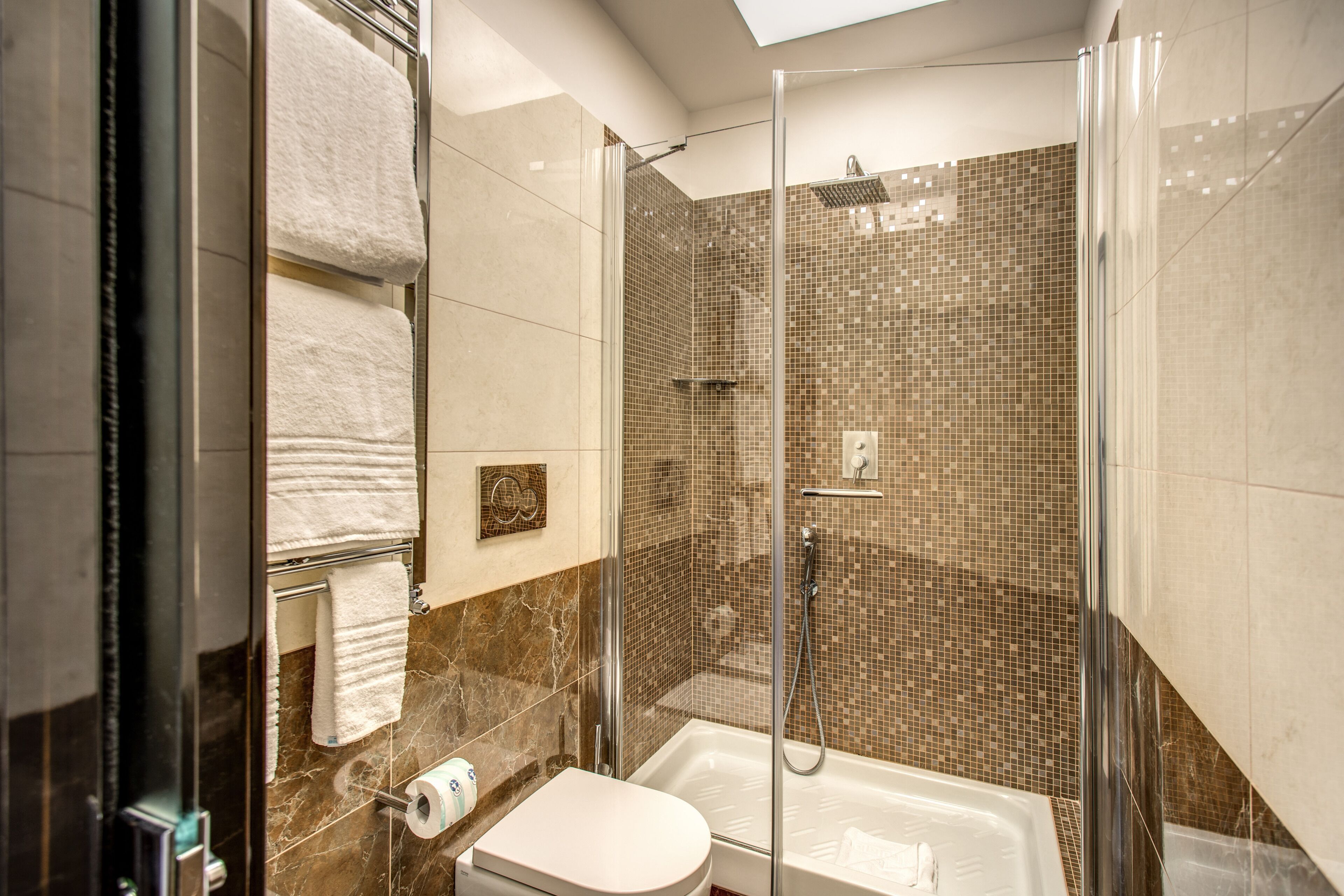 Un baño moderno con ducha envuelta en vidrio, bañera y retrete.