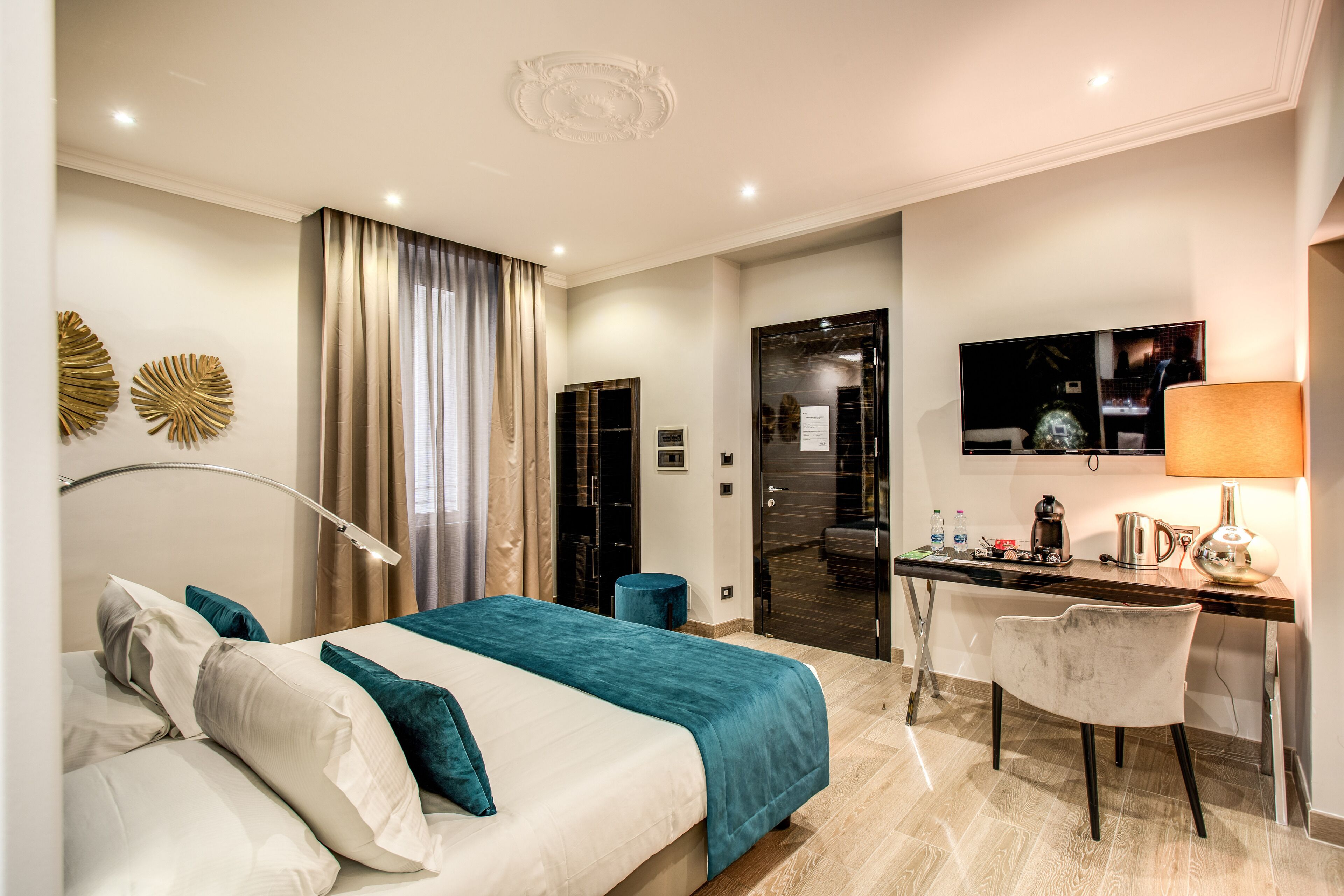 A modern hotel room with a bed, desk, chair, and a TV.