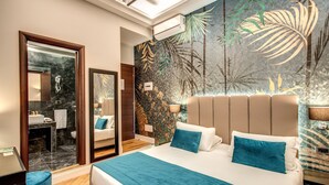 Quarto de hotel moderno com uma cama grande, banheiro com espelho e um mural temático tropical.