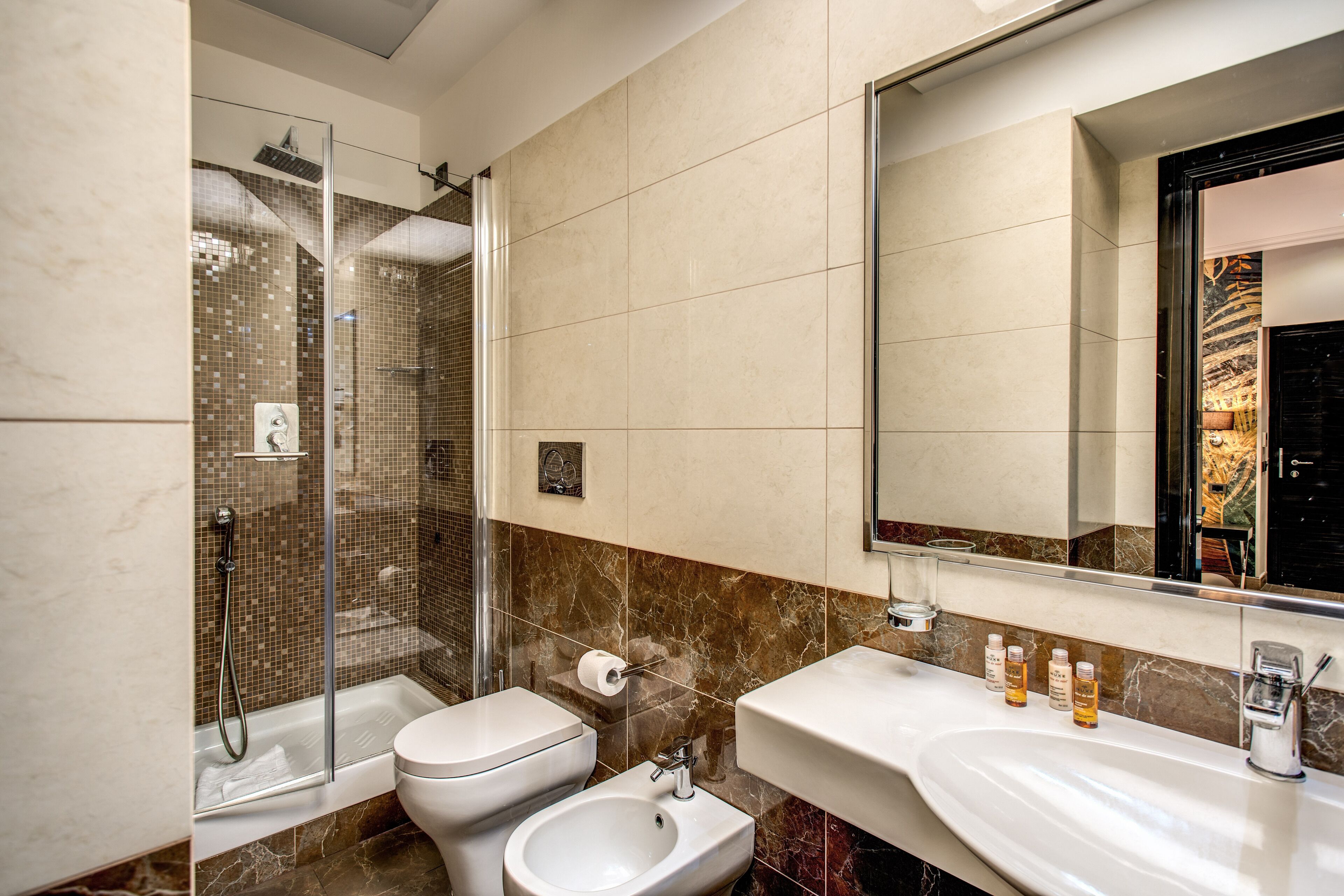 A modern bathroom with a glass-enclosed shower, a toilet, a bidet, and a vanity with a mirror.