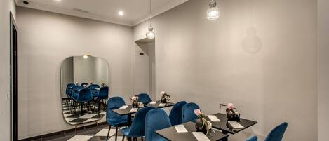 A conference room with a checkered floor, blue velvet chairs, and tables with flowers.