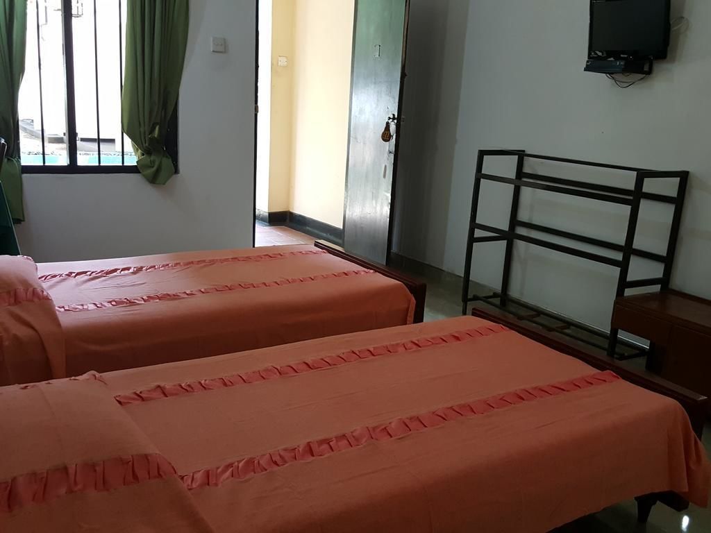 Una habitación con dos camas, un televisor en la pared y una puerta que da al exterior.
