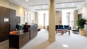 A reception area with a dark reception desk, a large pillar, and a seating area with sofas and chairs. - Soho Boutique Oviedo  (Oviedo)