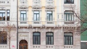 A multi-story building with a classical architectural style, featuring a central entrance with a large arched doorway and multiple balconies. - Soho Boutique Oviedo  (Oviedo)
