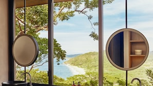 Un baño con dos lavamanos, un ventanal grande y vista a la playa.