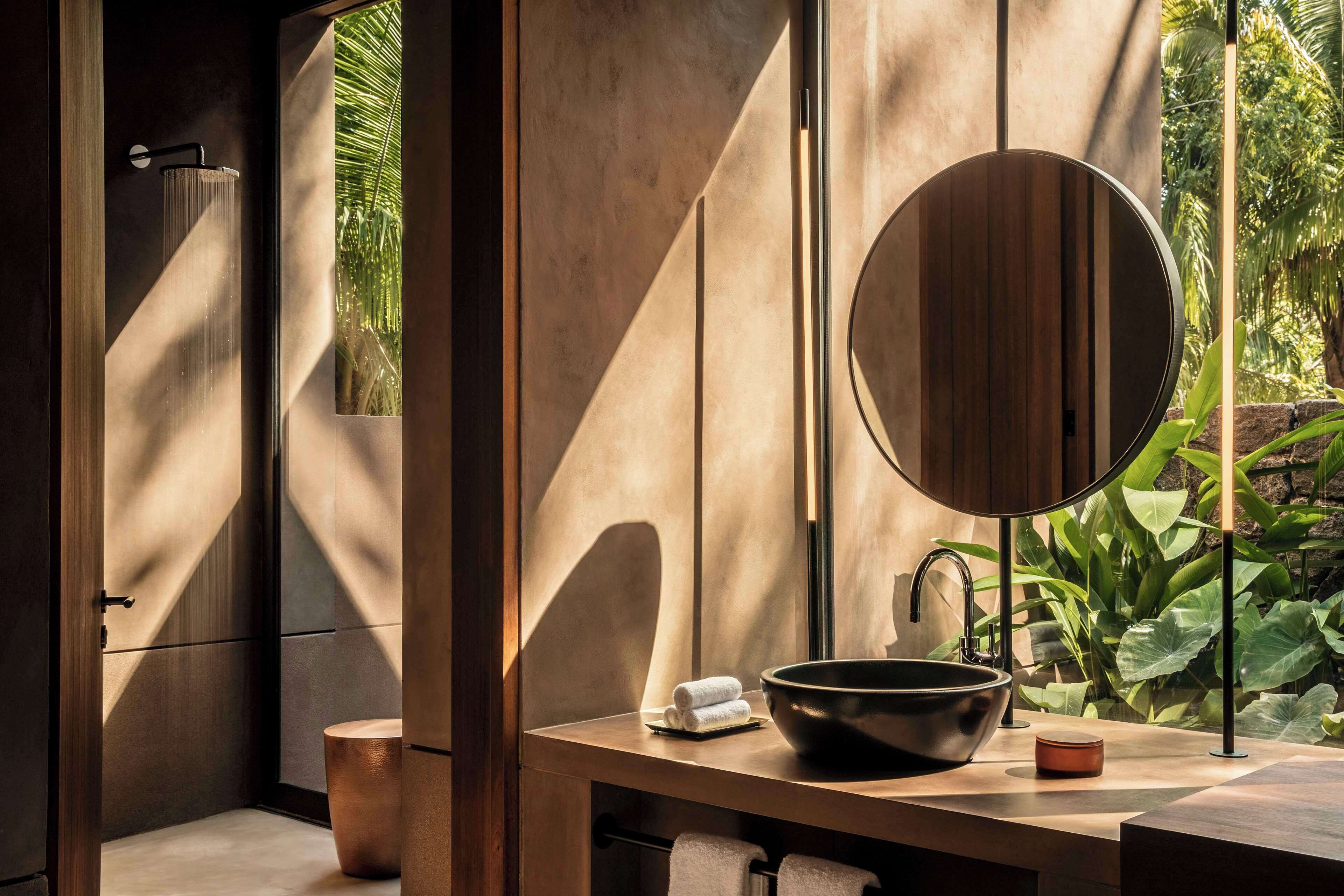 A modern bathroom with a large mirror, a round sink, and a towel rack.