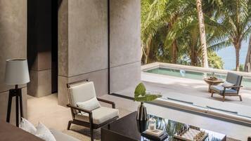 Una sala de estar moderna con un amplio ventanal que da a una piscina y palmeras.