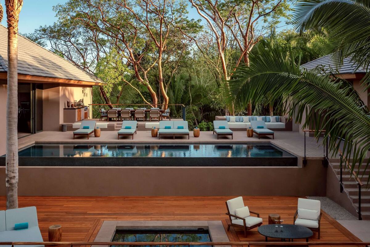 A modern outdoor pool area with lounge chairs and a wooden deck.