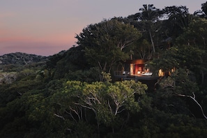 Una casa sull'albero isolata con un piccolo patio e un'unica stanza con camino.