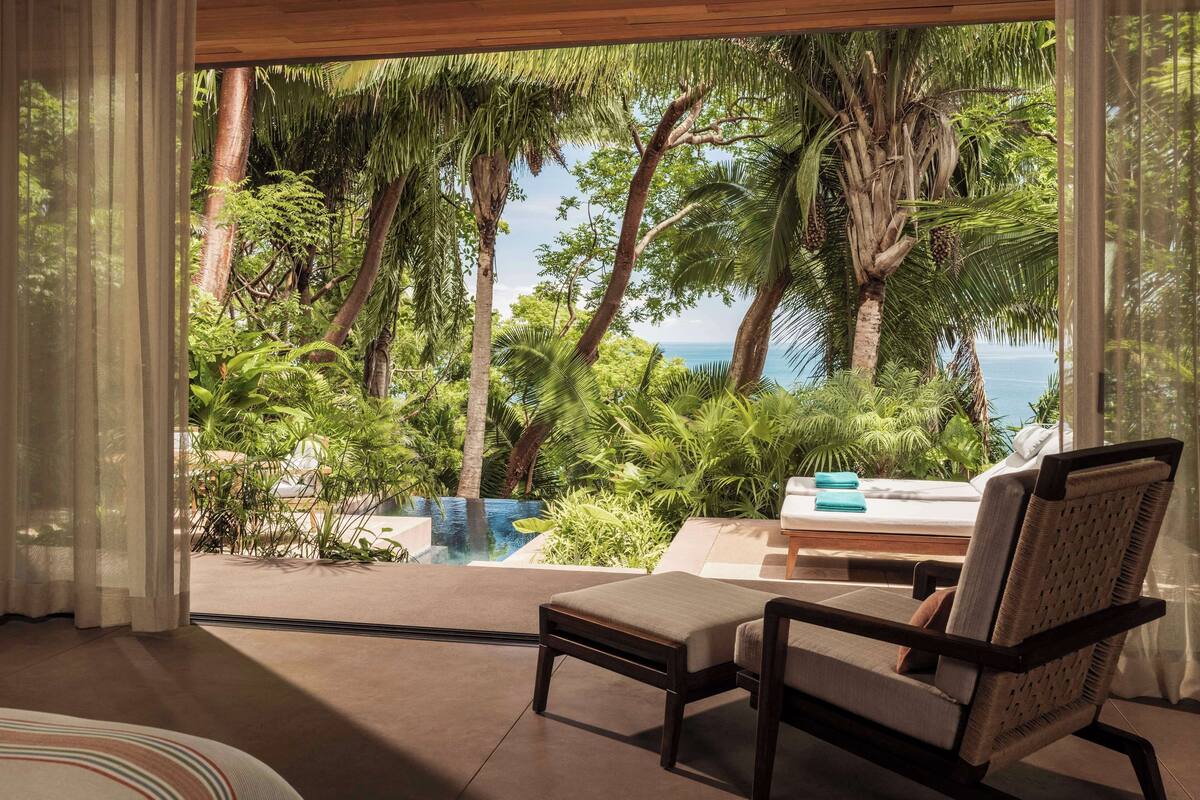 A room with a view of a tropical garden and ocean.