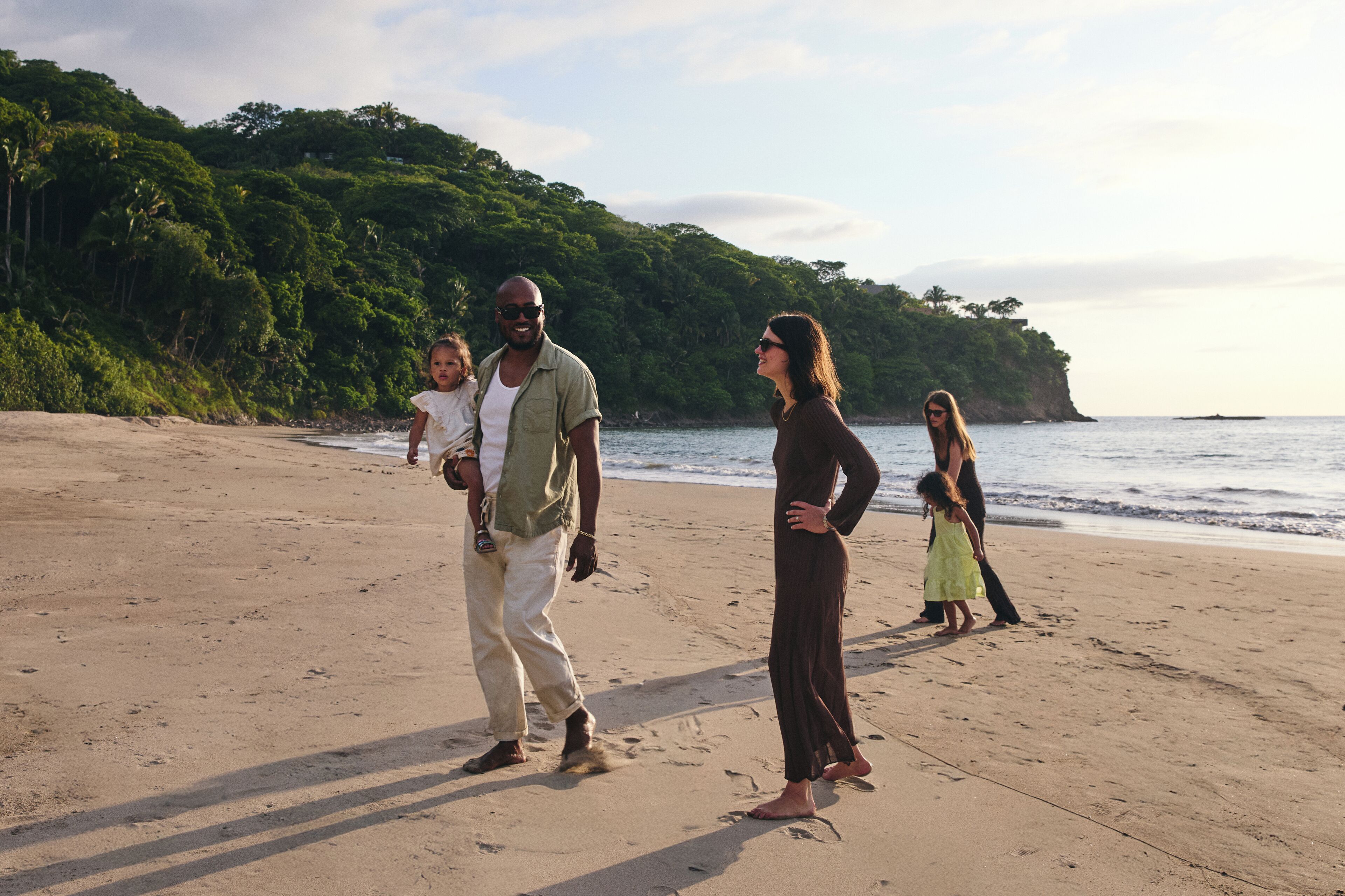 Una playa arenosa con un grupo de personas de pie y caminando.
