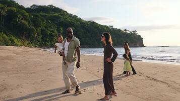 Una playa arenosa con un grupo de personas de pie y caminando.