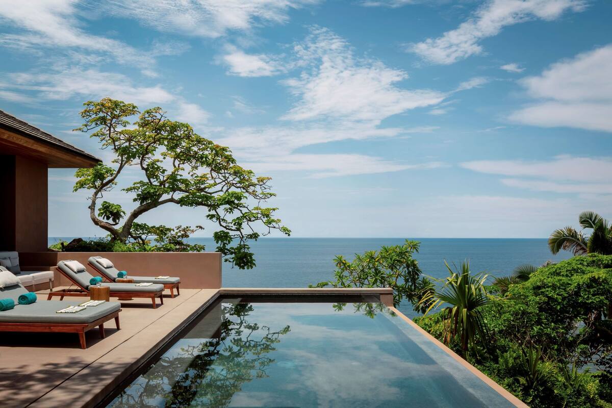 A poolside area with lounge chairs and a view of the sea.