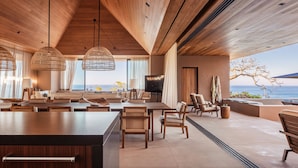 Un vestíbulo de hotel moderno y espacioso, con techo alto, vigas de madera y amplias ventanas que ofrecen vistas al océano.