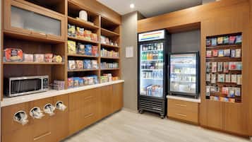 A kitchenette with wooden cabinets, a microwave, and a refrigerator stocked with beverages and snacks.