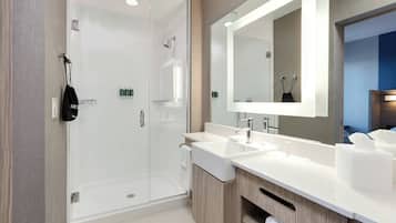 A modern bathroom with a glass-enclosed shower, two sinks, a large mirror, and wooden cabinetry.