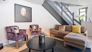 A modern living room with a sofa, armchairs, a coffee table, and a staircase. - The Edge Suite - hiphipstay (Dublin)