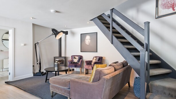 A modern living room with a sofa, chairs, a coffee table, and a staircase. - The Edge Suite - hiphipstay (Dublin)