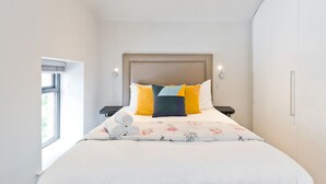 A modern bedroom with a large bed, a headboard, bedside tables, and a window. - The Edge Suite - hiphipstay (Dublin)
