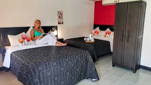 Ein Hotelzimmer mit zwei Betten, einem Kleiderschrank und einem Nachttisch mit Lampe.